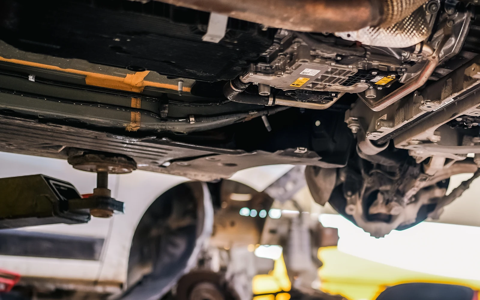 Underside of a raised vehicle, showing drivetrain components and the lift support.